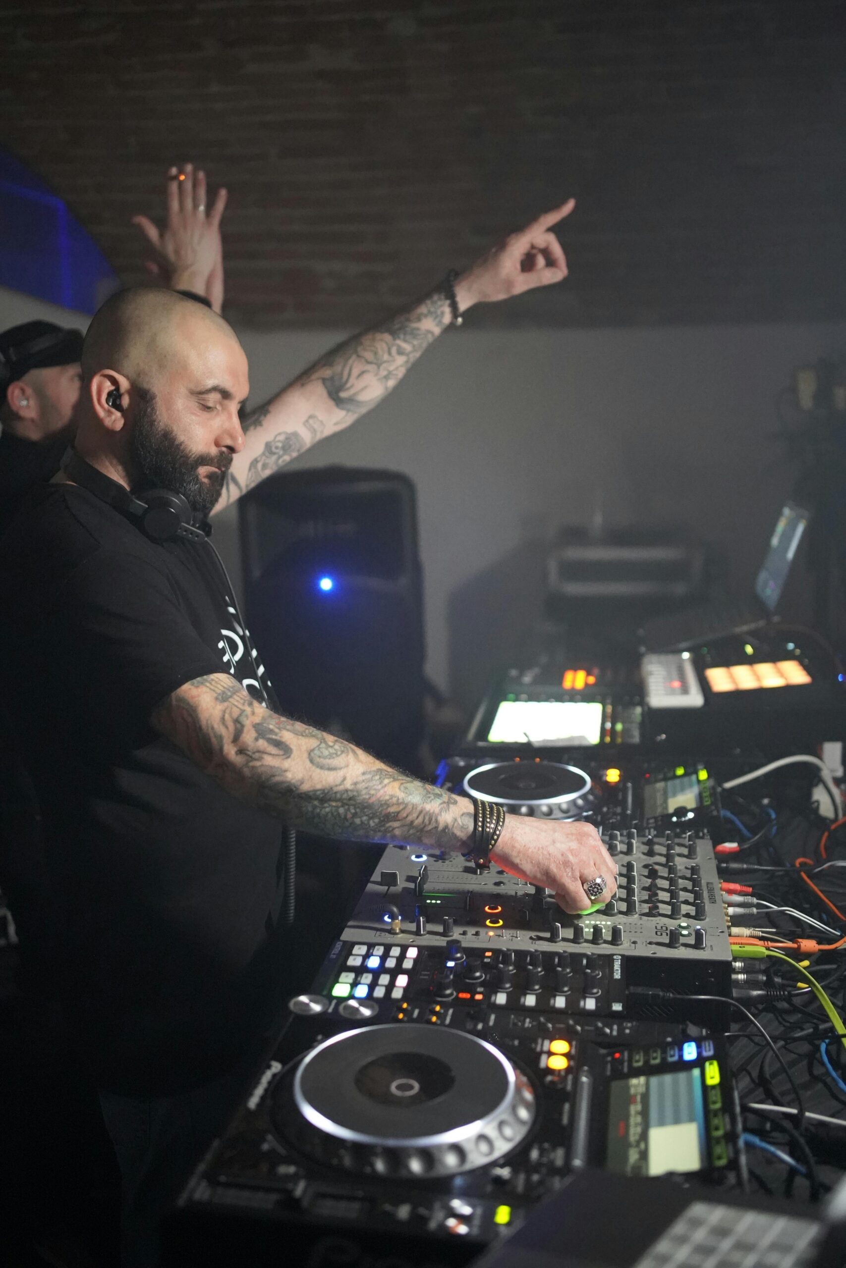 A DJ mixes tracks at a lively indoor music event, engaging the crowd.